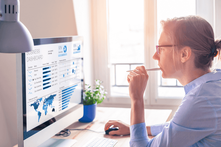 Woman with pen in mouth looking at computer screen. 