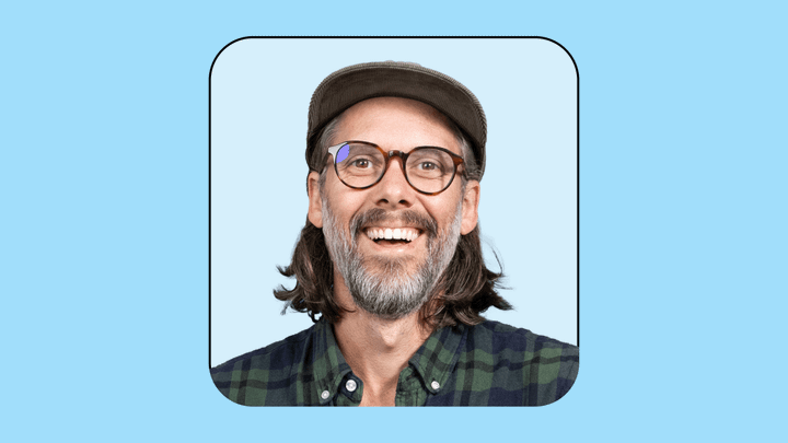 Gregory John's headshot on a light blue background surrounded by a black frame outline.