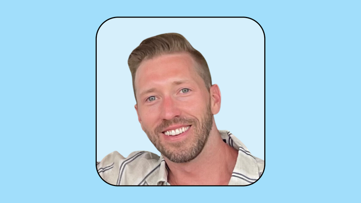 A headshot of Nick Carroll on a light blue background.