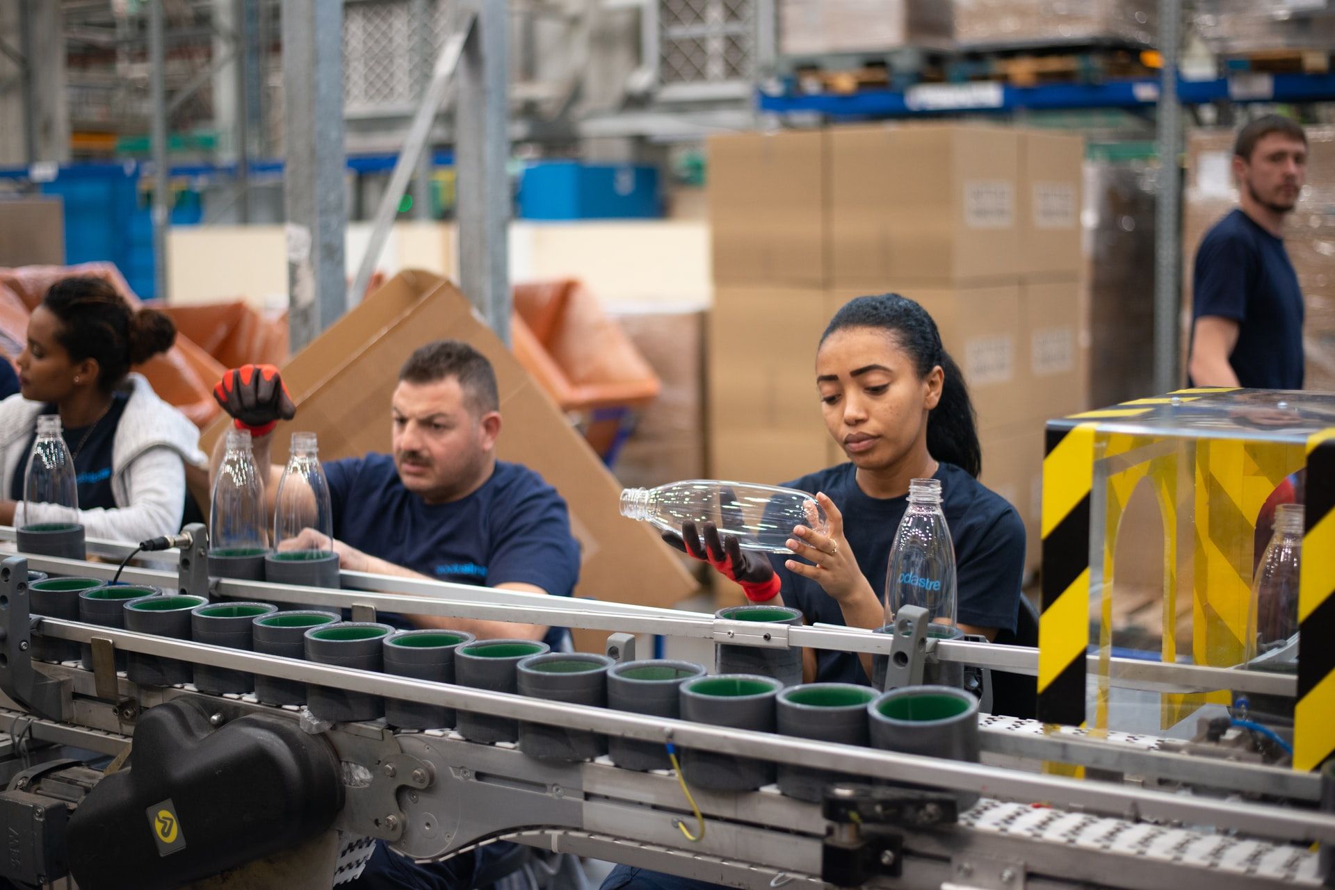 Workers inspecting plastic bottles on an assembly line