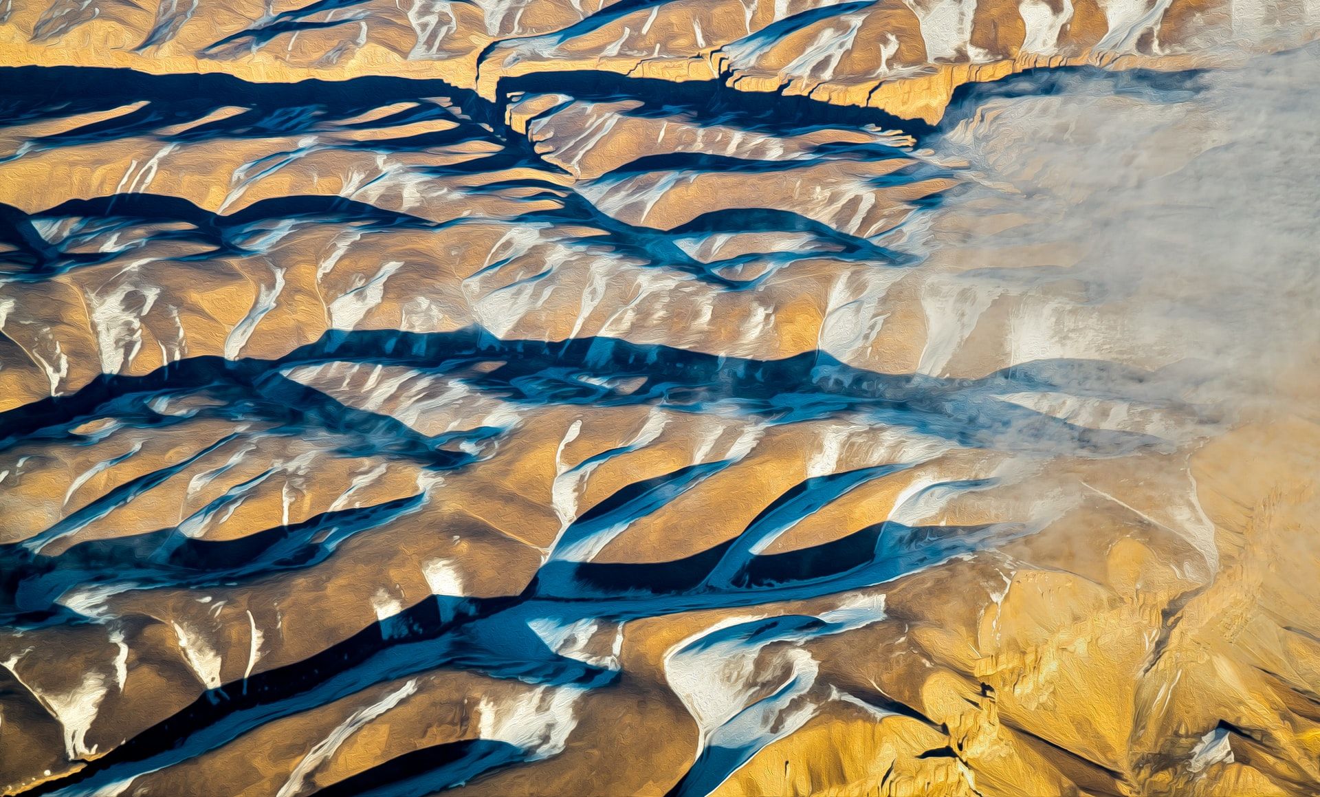 View of foothills from an airplane with shadows making folds in the land starkly visible.