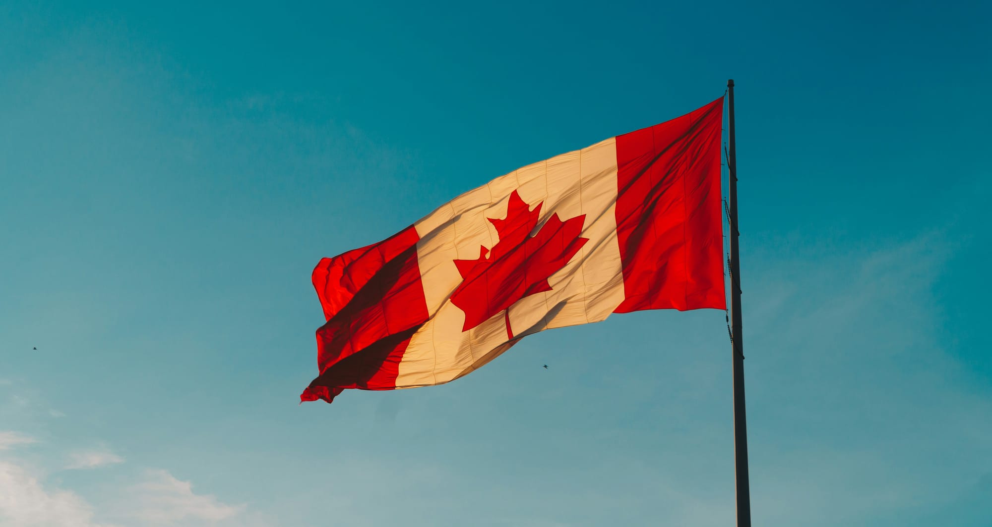 A Canadian flag flying against a blue sky in Windsor, Canada.