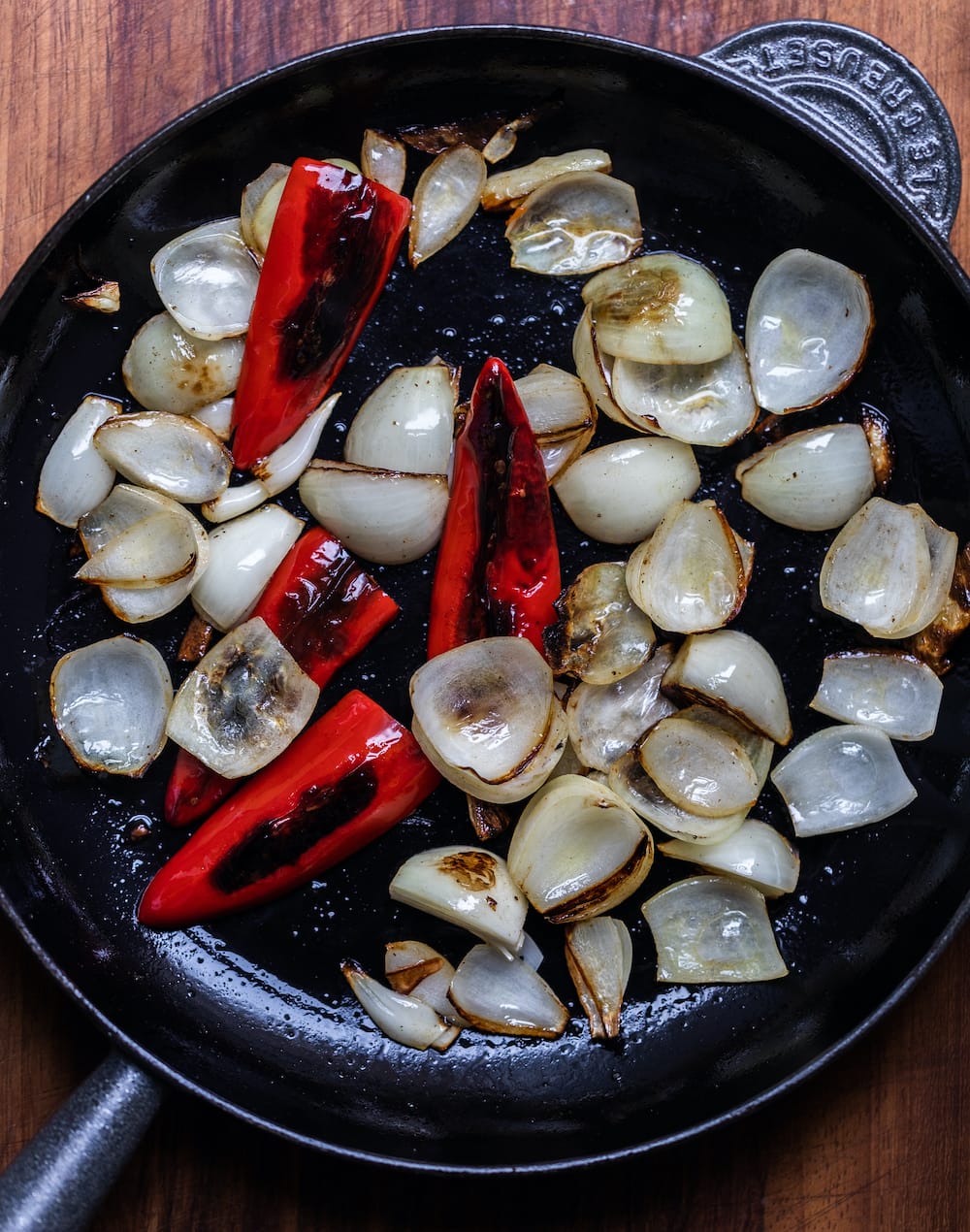 Overhead shot of chillies and onions for slow cooker Texas pulled pork cooking in a stainless pan
