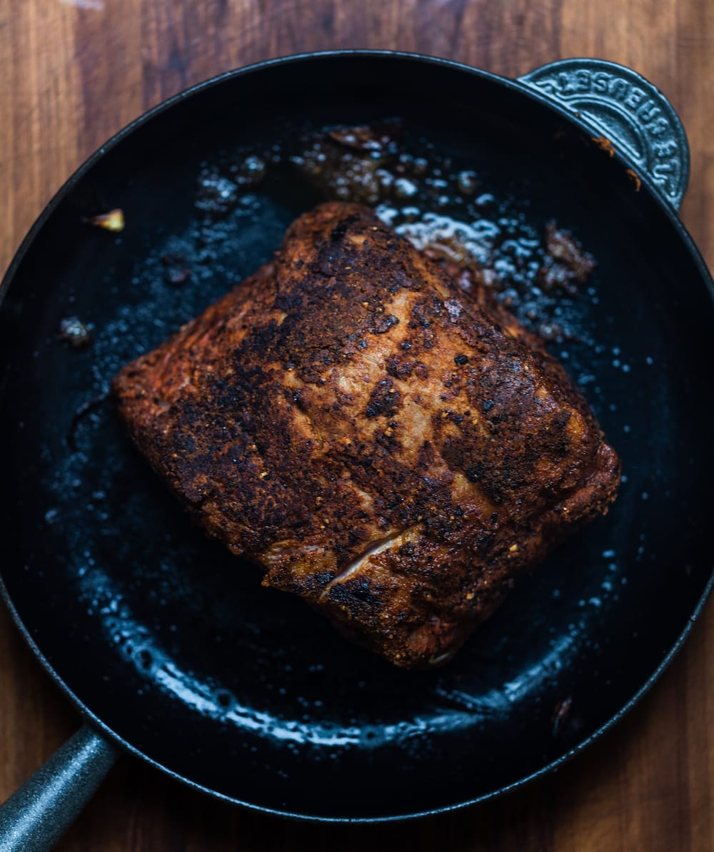 Overhead shot of seasoned slow cooker Texas pulled pork in a cast iron skillet