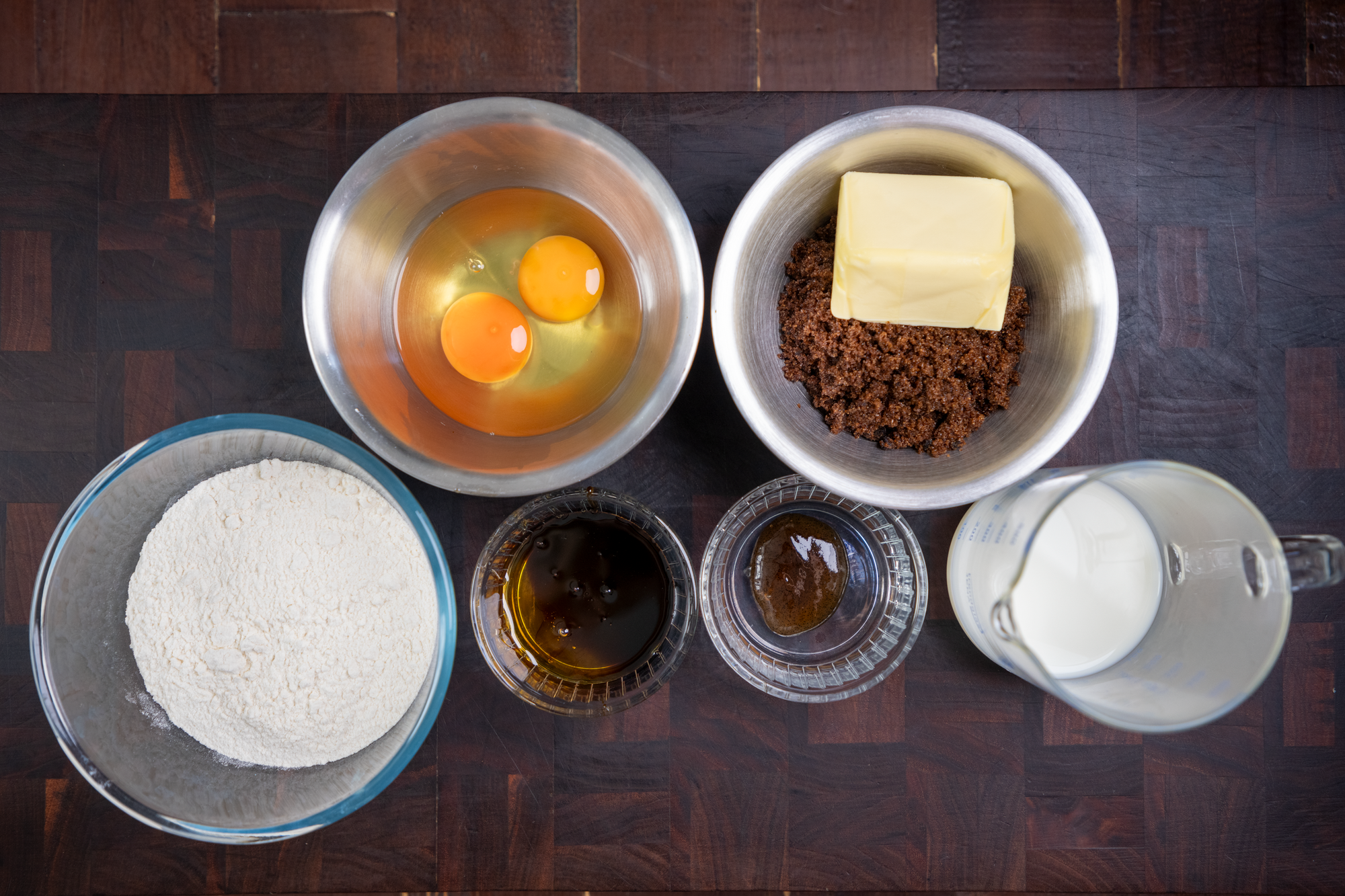 Overhead shot of ingredients for a sticky toffee pudding sponge on a wooden table and wooden chopping board. 