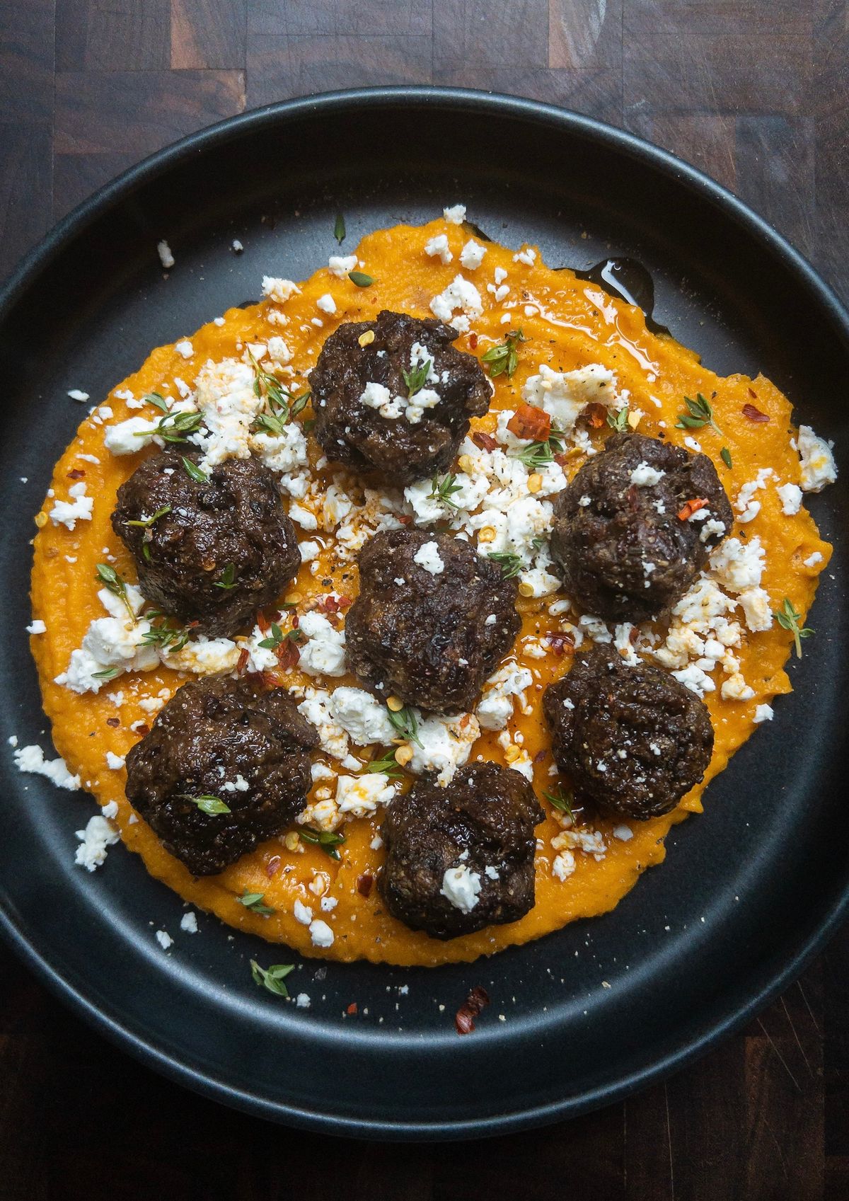Overhead shot of beef and liver meatballs with sweet potato puree on a black plate