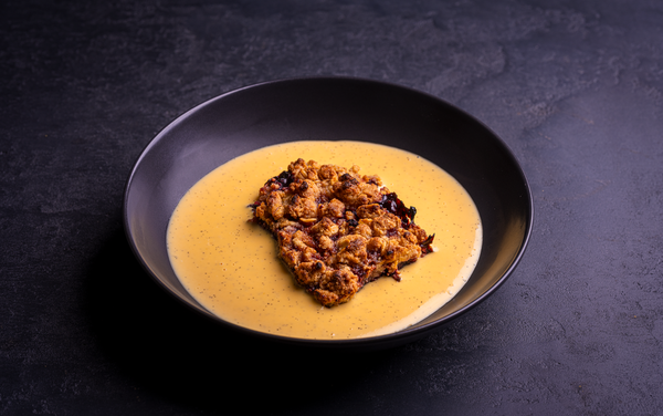 Wild Blackberry Crumble with Real Vanilla Custard in a black bowl on a black background