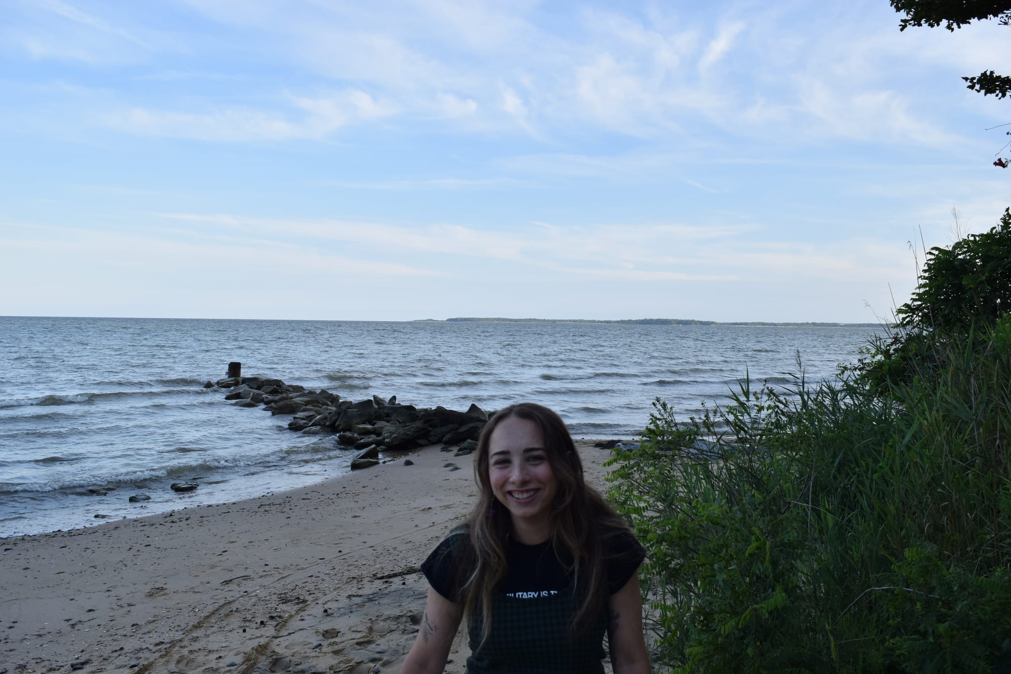 Carly Rizzuto standing on a beach with visible vegetation, sand, and water.