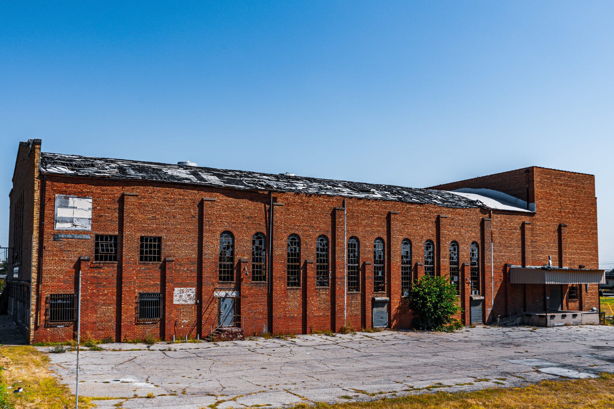 A brick building with arched windows, in significant disrepair.