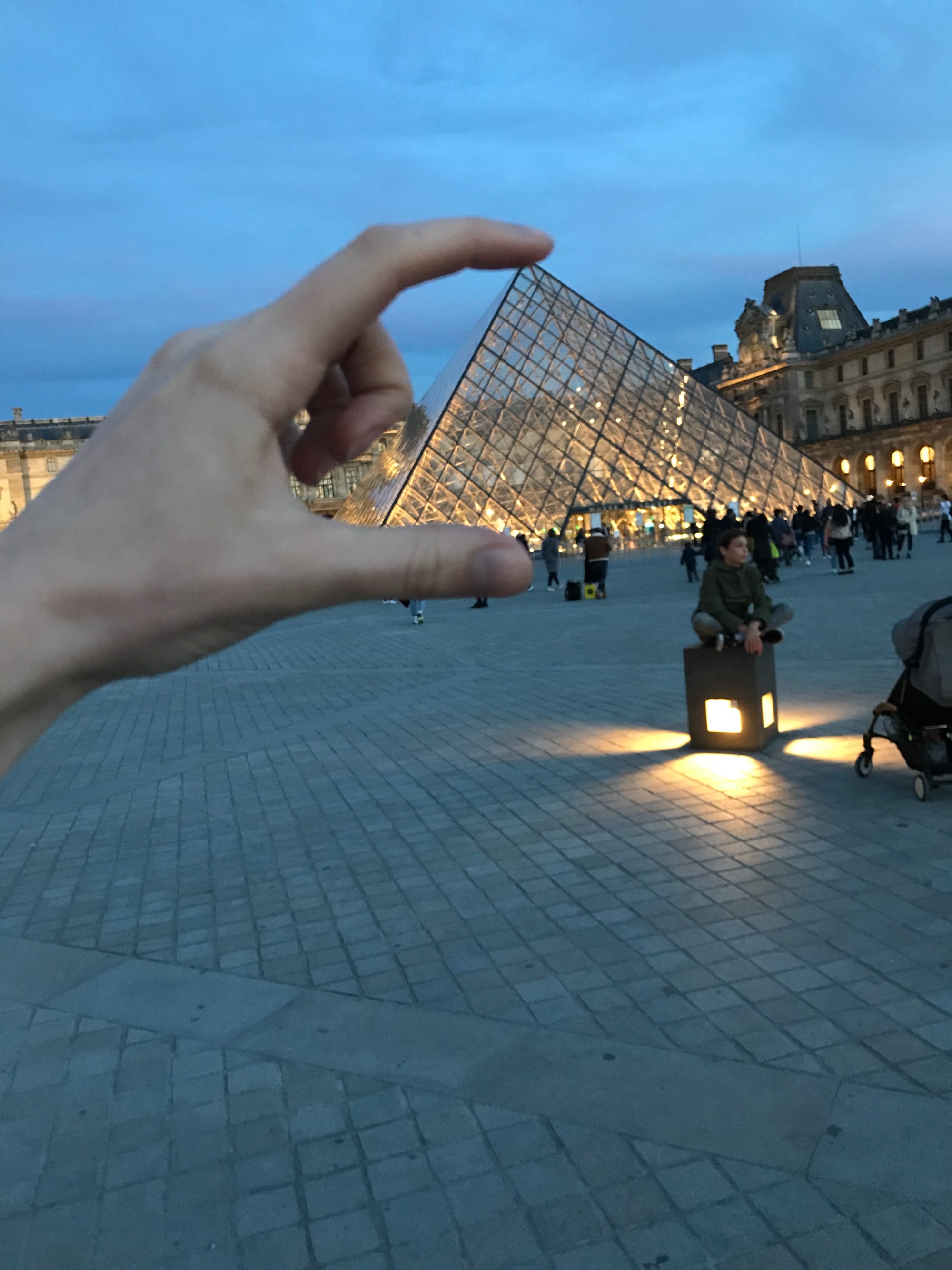 A hand encircles the Louvre in the background.