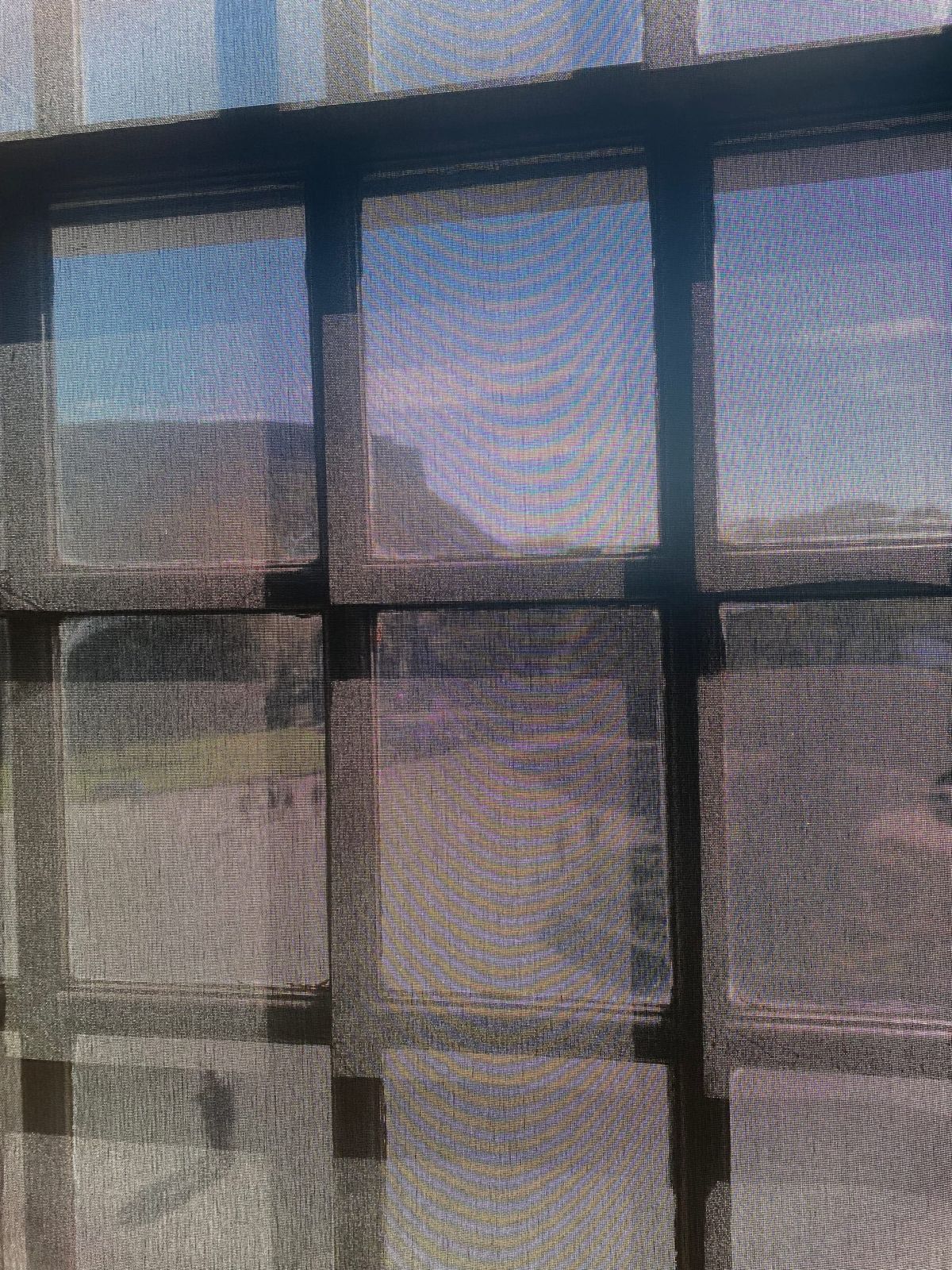 Salisburys crags viewed through a semi transparent blind over a window.