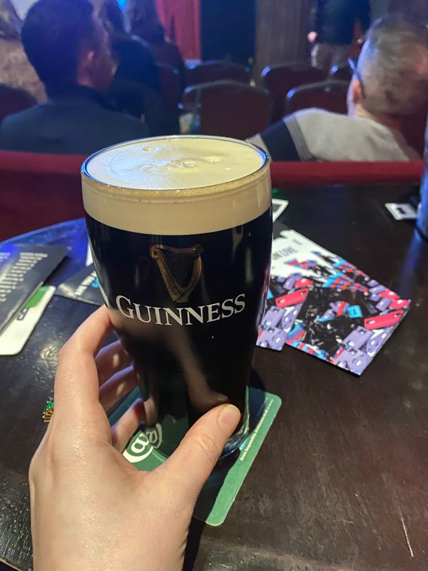 a hand reaches out to a pint of Guinness.