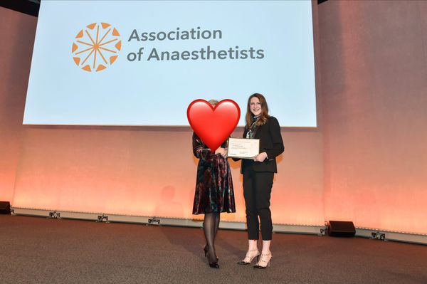 A woman in a black trousers iit revived a certificate from the association of anaesthetists.