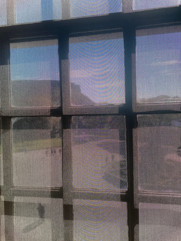 Salisburys crags viewed through a semi transparent blind over a window.