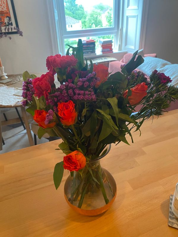A vase containing a bouquet of brightly coloured flowers.