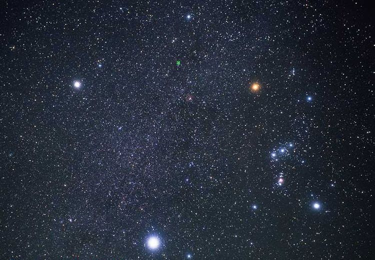 Field of stars in the night sky. The three brightest form a triangle to the left of the constellation Orion.