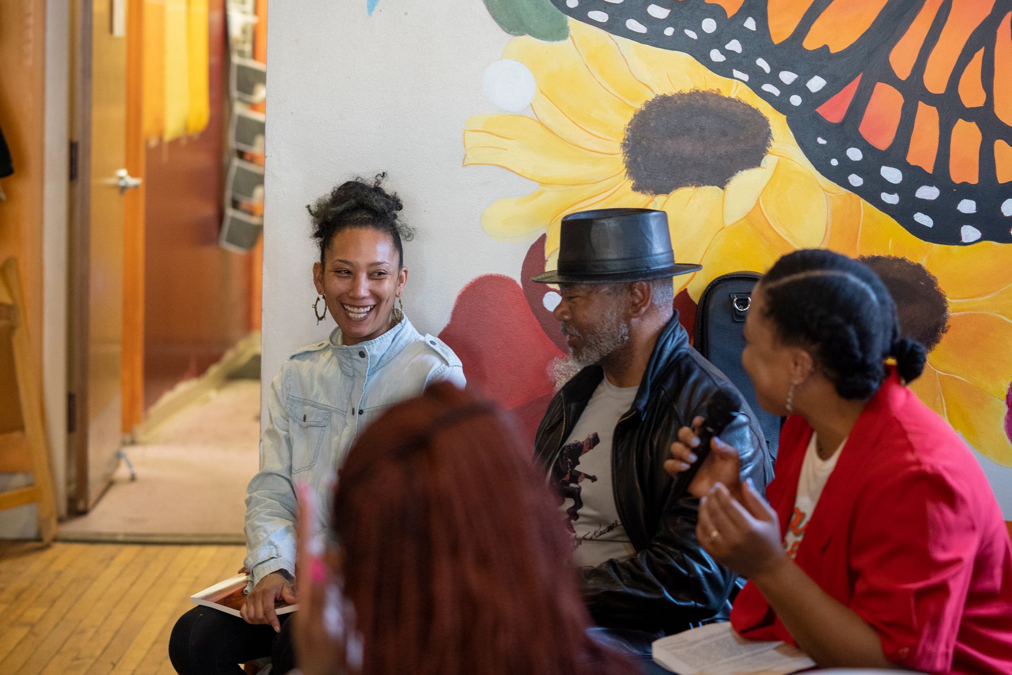 Four people sitting in conversation with left-most woman laughing