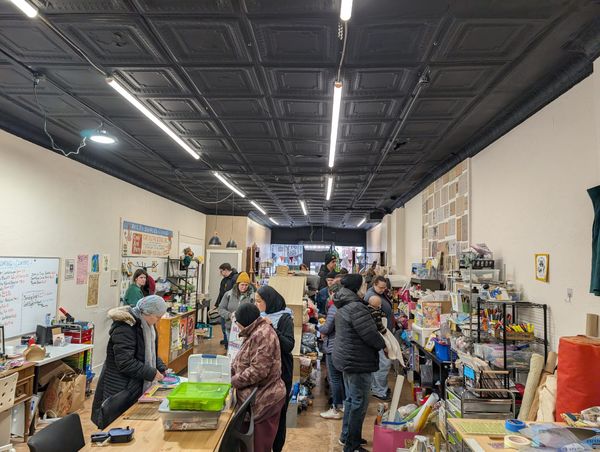 Shoppers peruse the inside of a small shop filled with shelves and tables and other assorted items. 