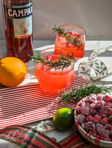 bright red campari cocktails garnished with rosemary and cranberries