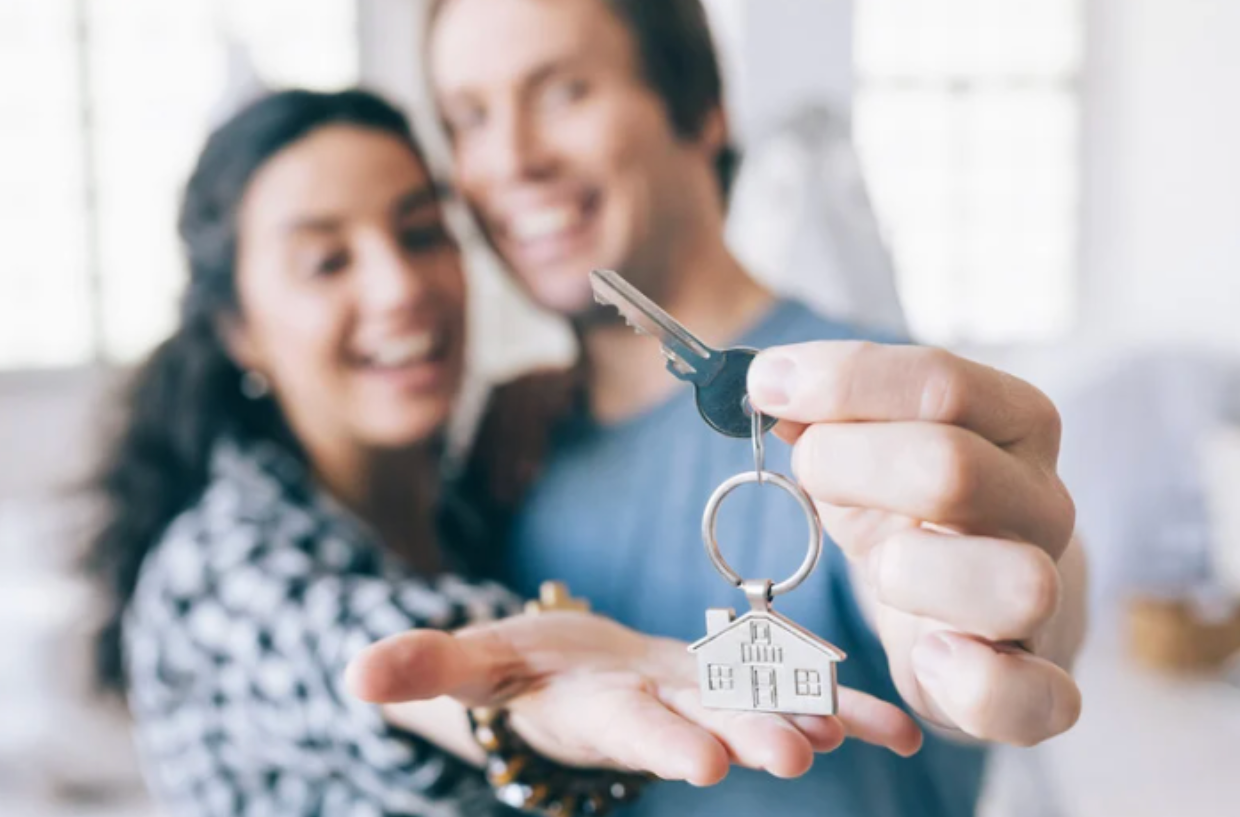 Smiling couple holding house keys after relocating to Ottawa for luxury home purchase.