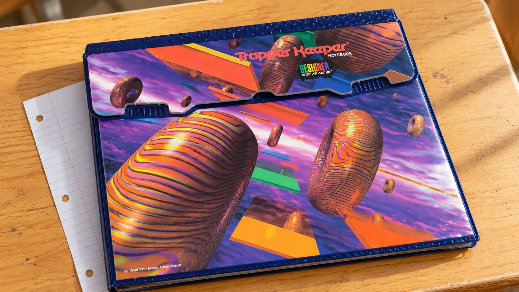 A patterned Trapper Keeper binder on a desk