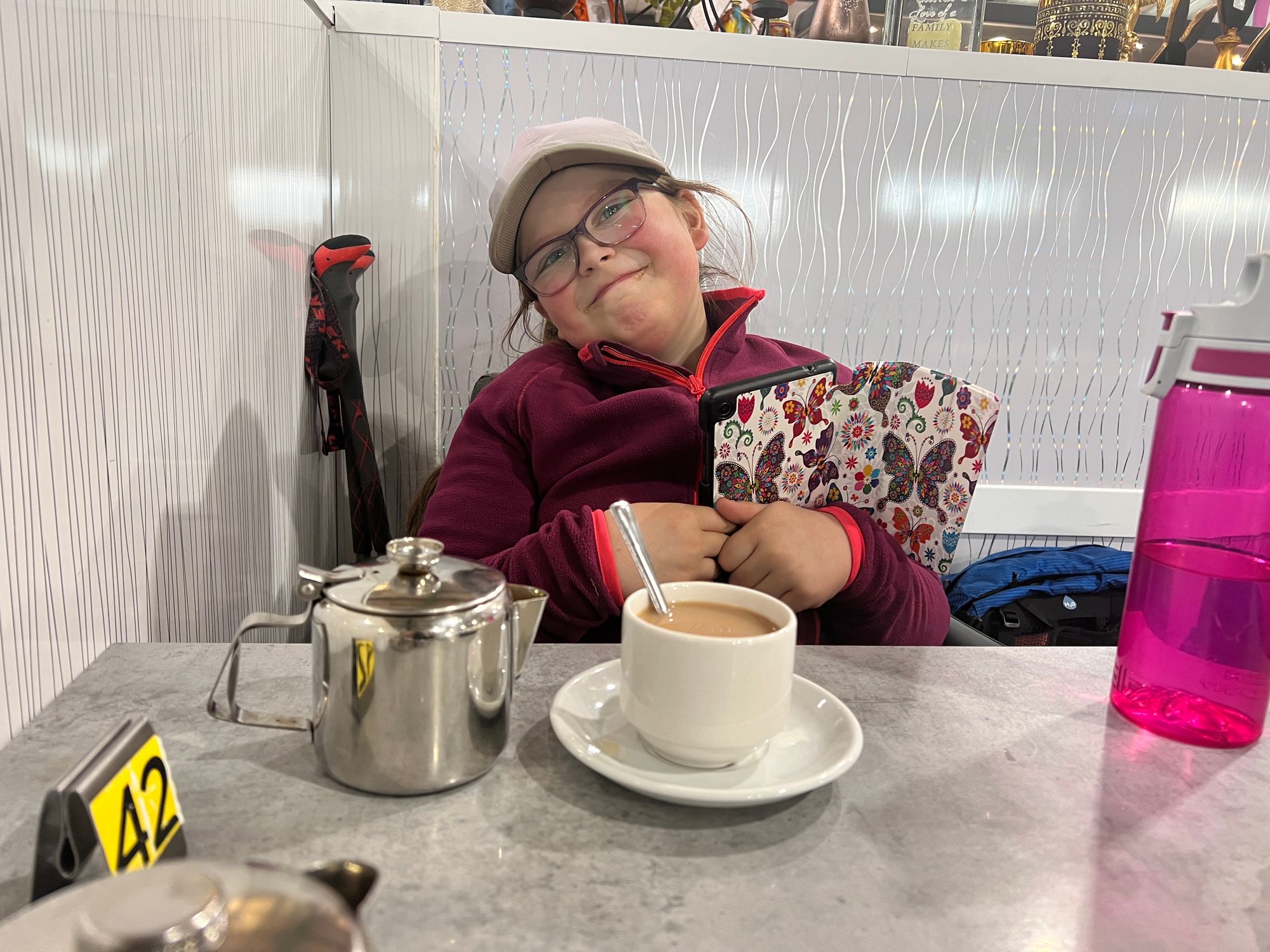 Enjoying a cup of tea (I asked Eve to do a ‘cheesy’ smile) and doing some home education (reading) on her tablet)