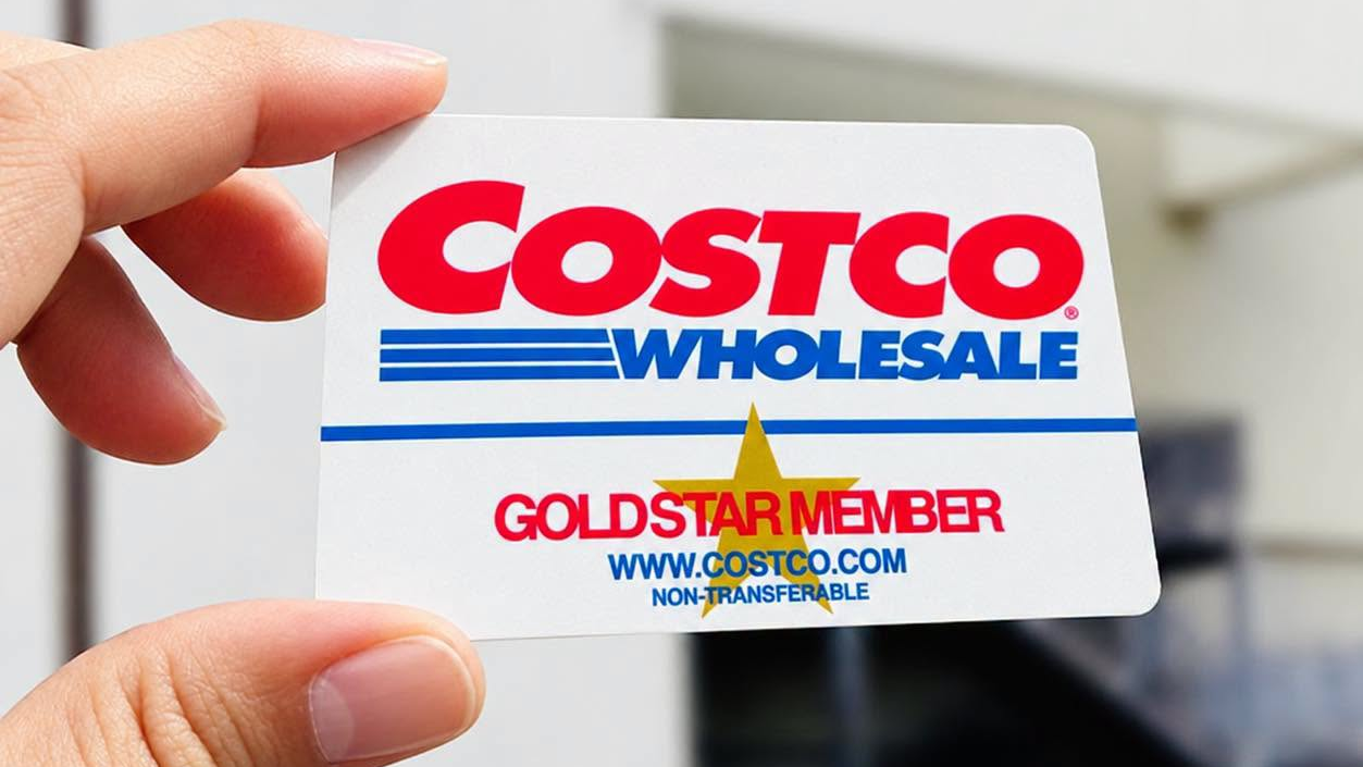 手持好市多 Costco 會員卡，背景為倉儲店外牆招牌。