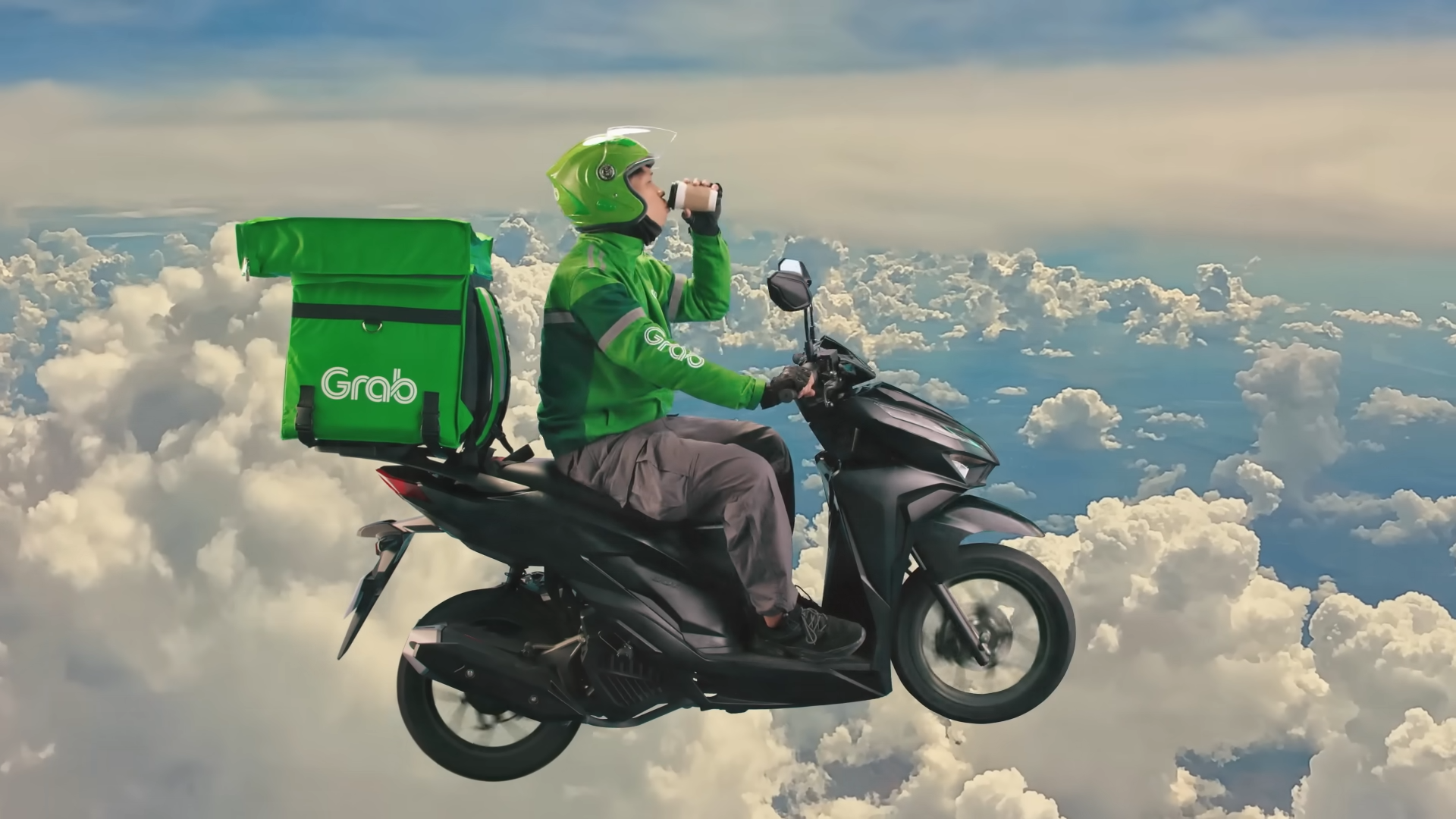 Grab 外送員坐在機車上喝飲料，後方載有綠色外送箱，背景為雲海。