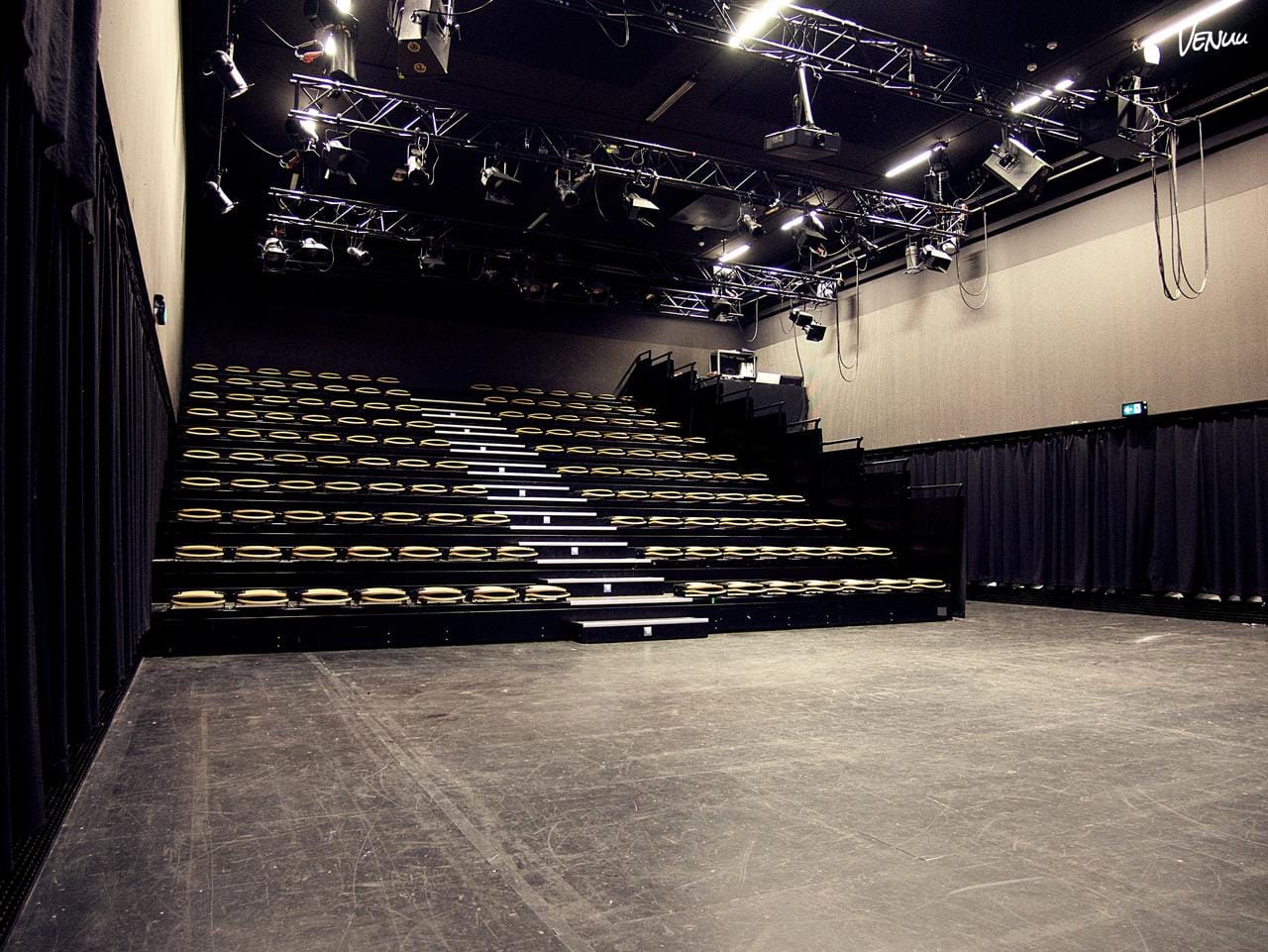 Unikt konferencelokale i teatersal med scene og dramatisk stemning.