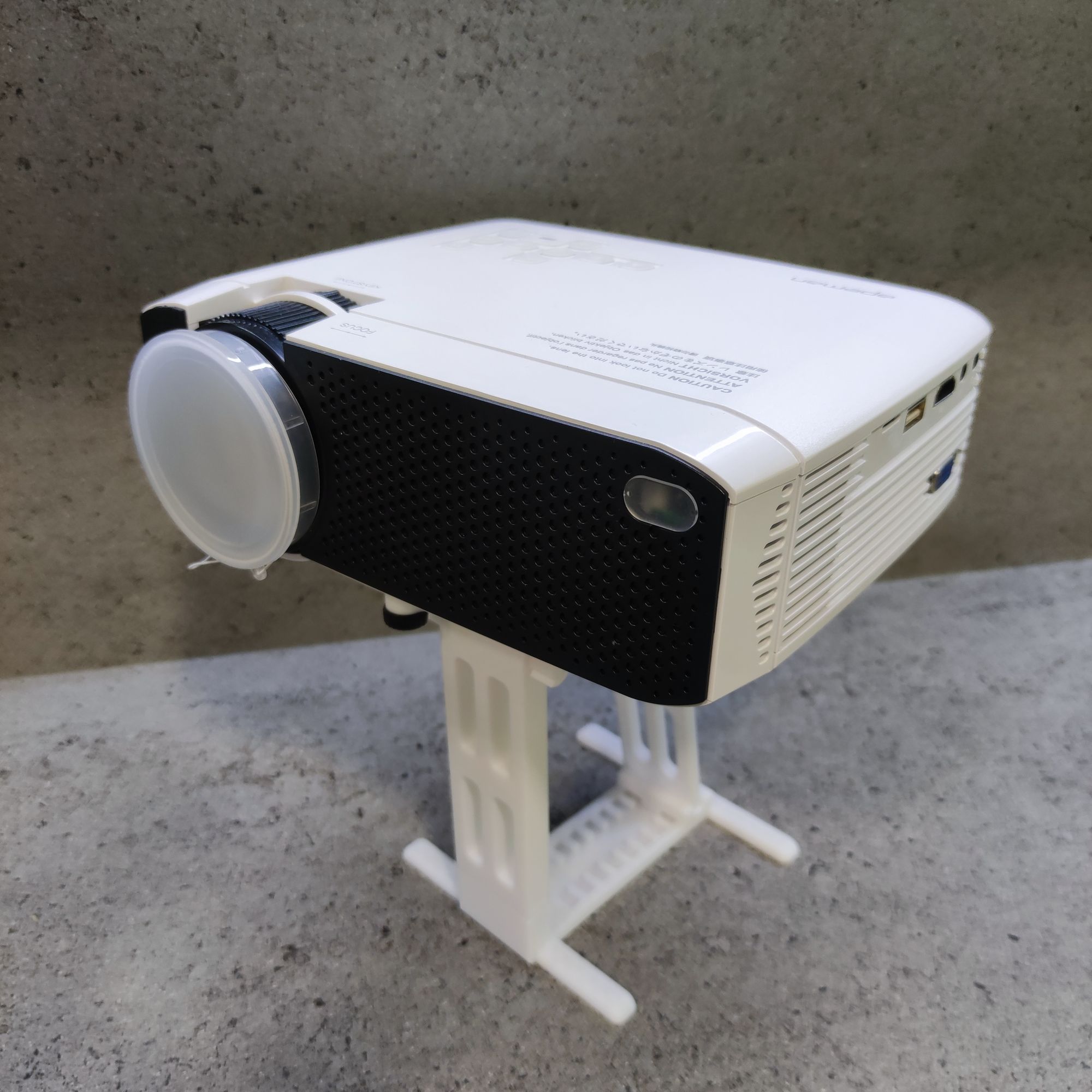 A white and black projector on a grey surface

Description automatically generated