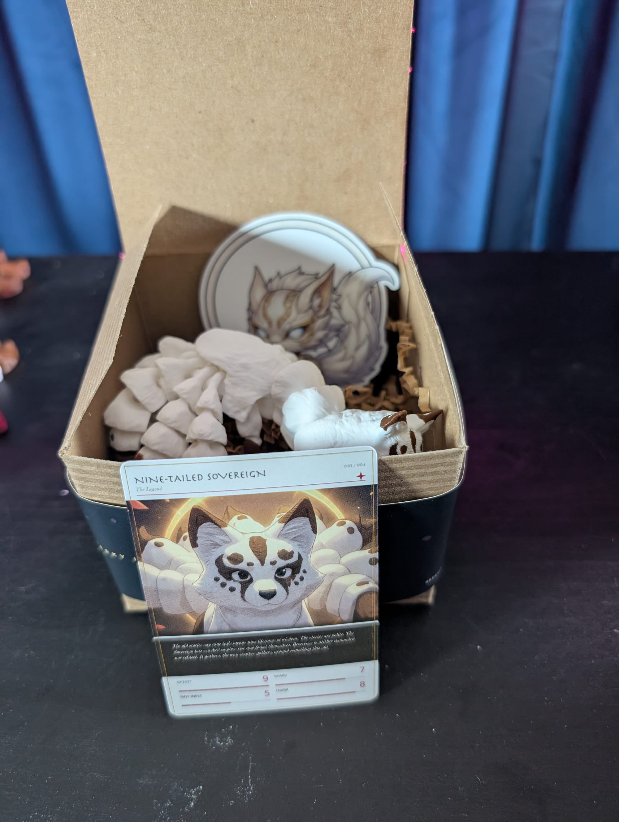 An opened Wave 1 box revealing the printed Nine-Tailed Sovereign figure and its collector card