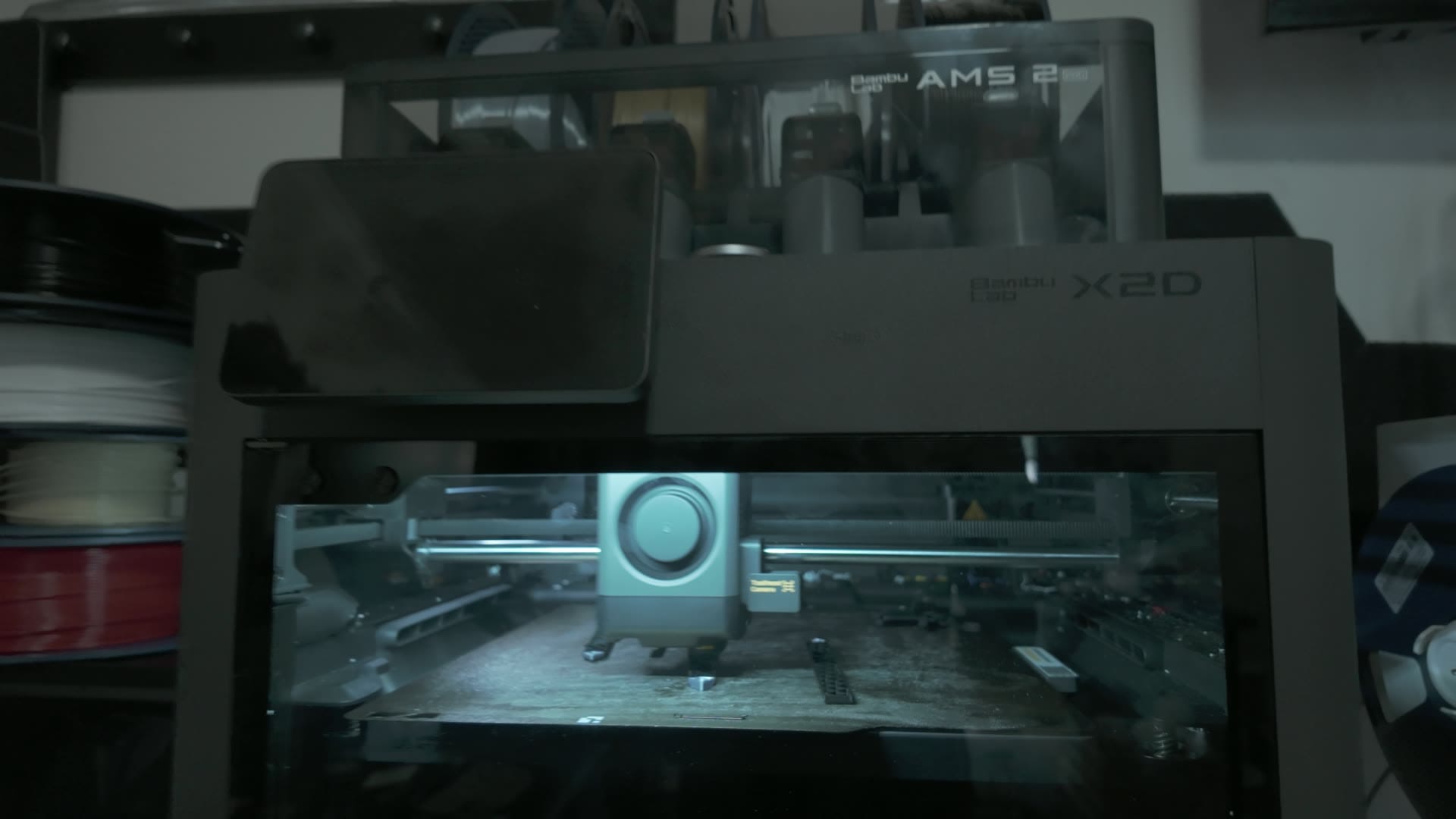 Bambu Lab X2D with the AMS 2 Pro mounted on top, printing in Devon's Geeky Inc print shop