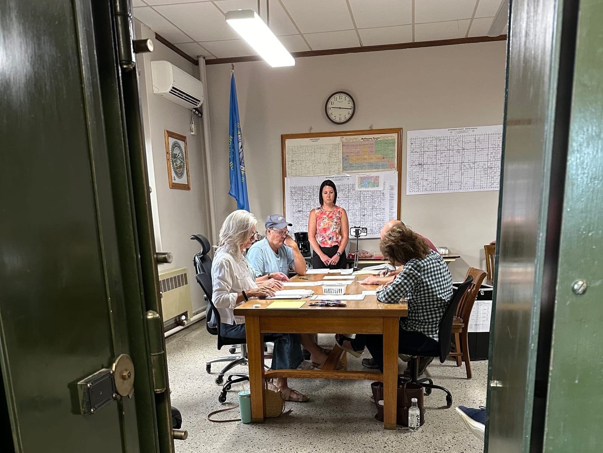 McPherson County Auditor Lindley Howard (standing) watches citizens conduct a re-audit of the 2024 primary election