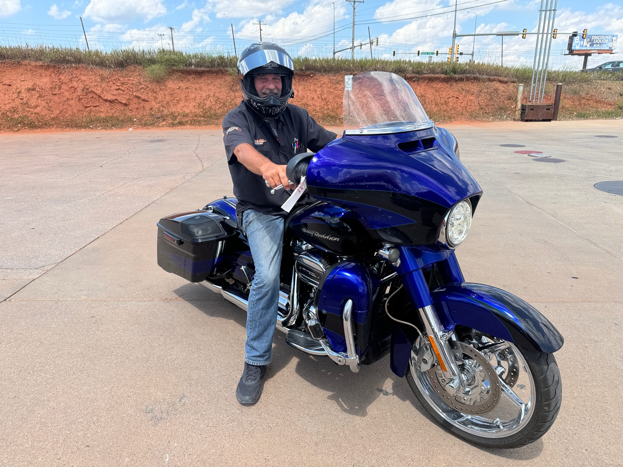 A man sits atop a blue motorcycle ahead of the Sturgis Motorcycle Rally