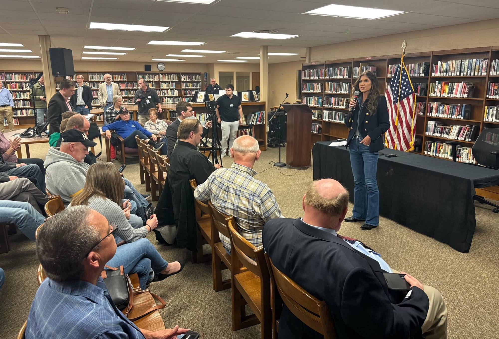 South Dakota Gov. Kristi Noem speaks in front of a room full of people in a library