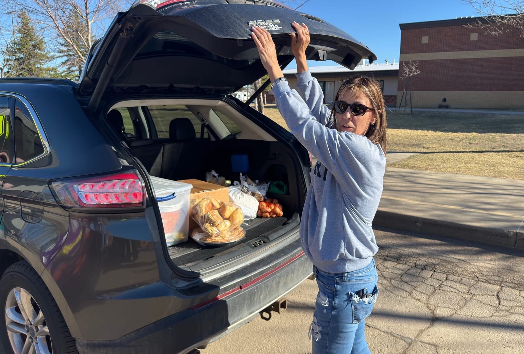 Feeding South Dakota volunteer Cassie Armstrong makes a final check before closing the hatch on a client's car at the mobile food bank on March 27, 2025,