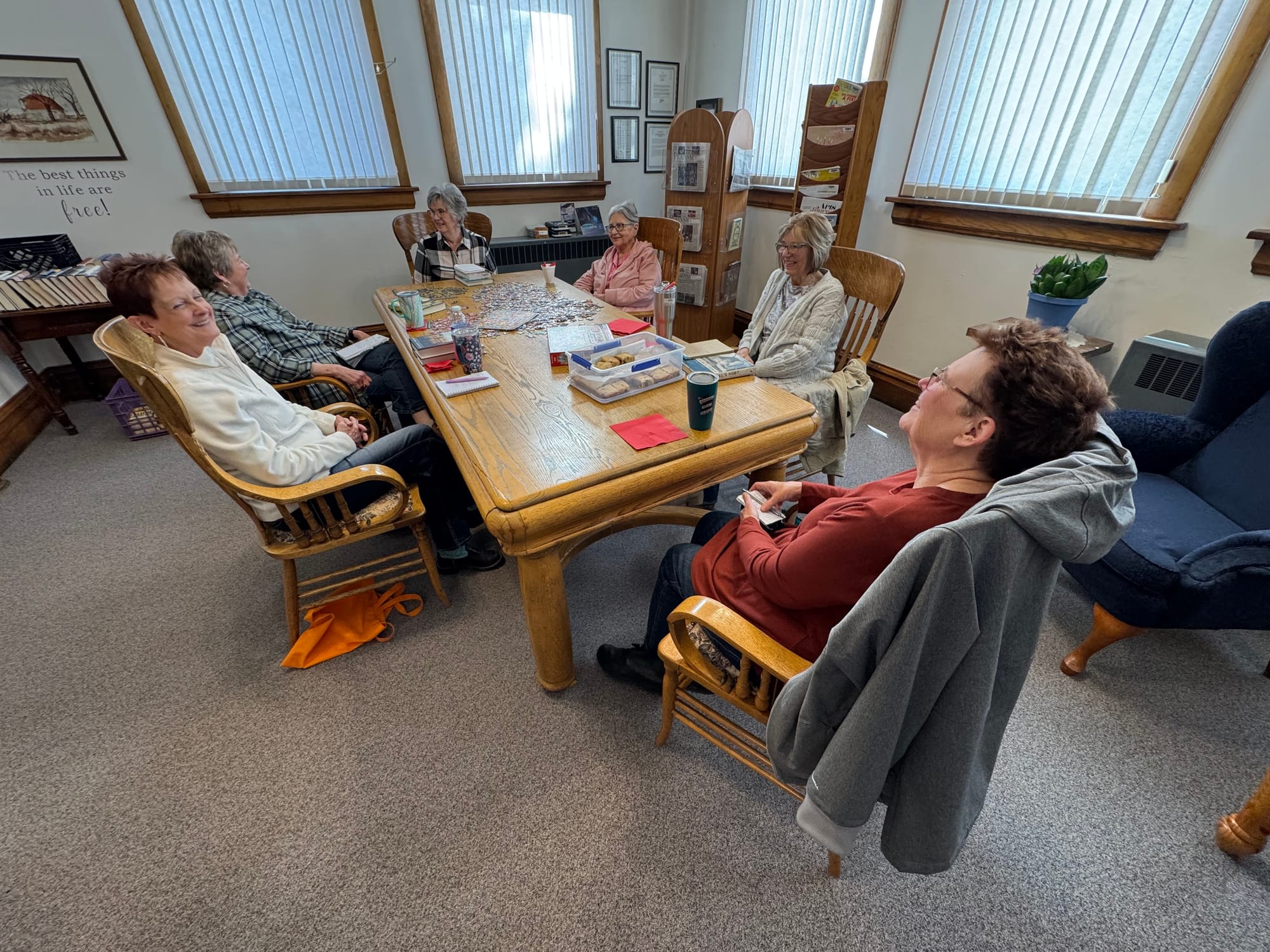 Library patrons attend a monthly book club attended by a group of people sitting around a table.