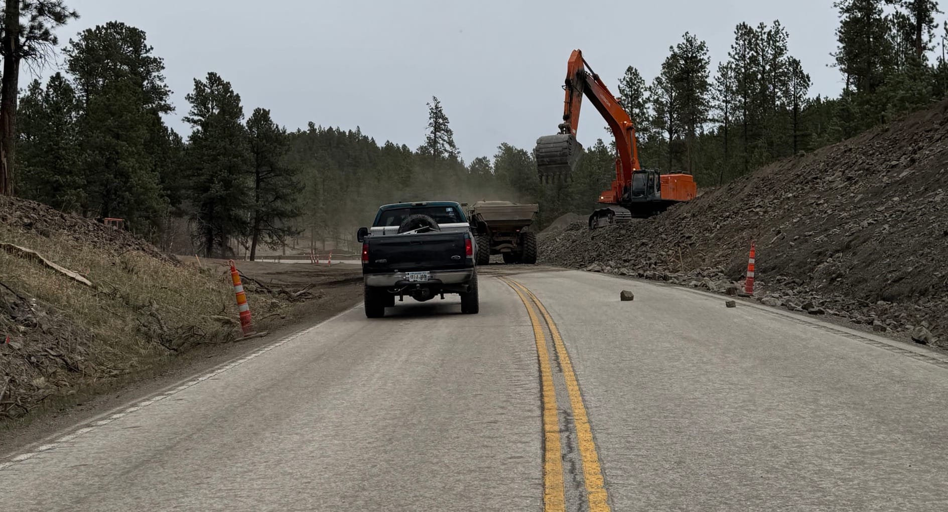 A truck drives down US 385 in the Black Hills as construction equipment sits on the right-hand side of the road