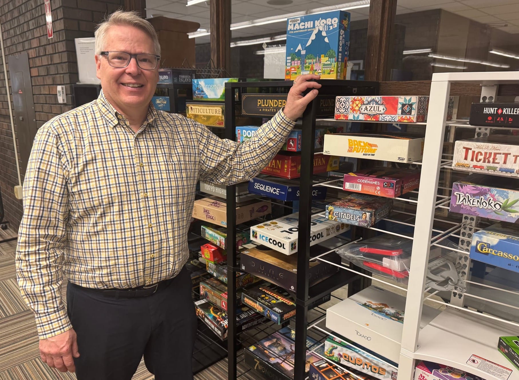 Mitchell Public Library director Kevin Kenkel stands next to a wall of board games that patrons can play at the library