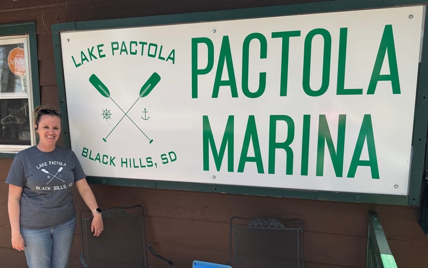 Angie Weaver, co-owner of the Pactola Marina, stands next to a sign outsider her business