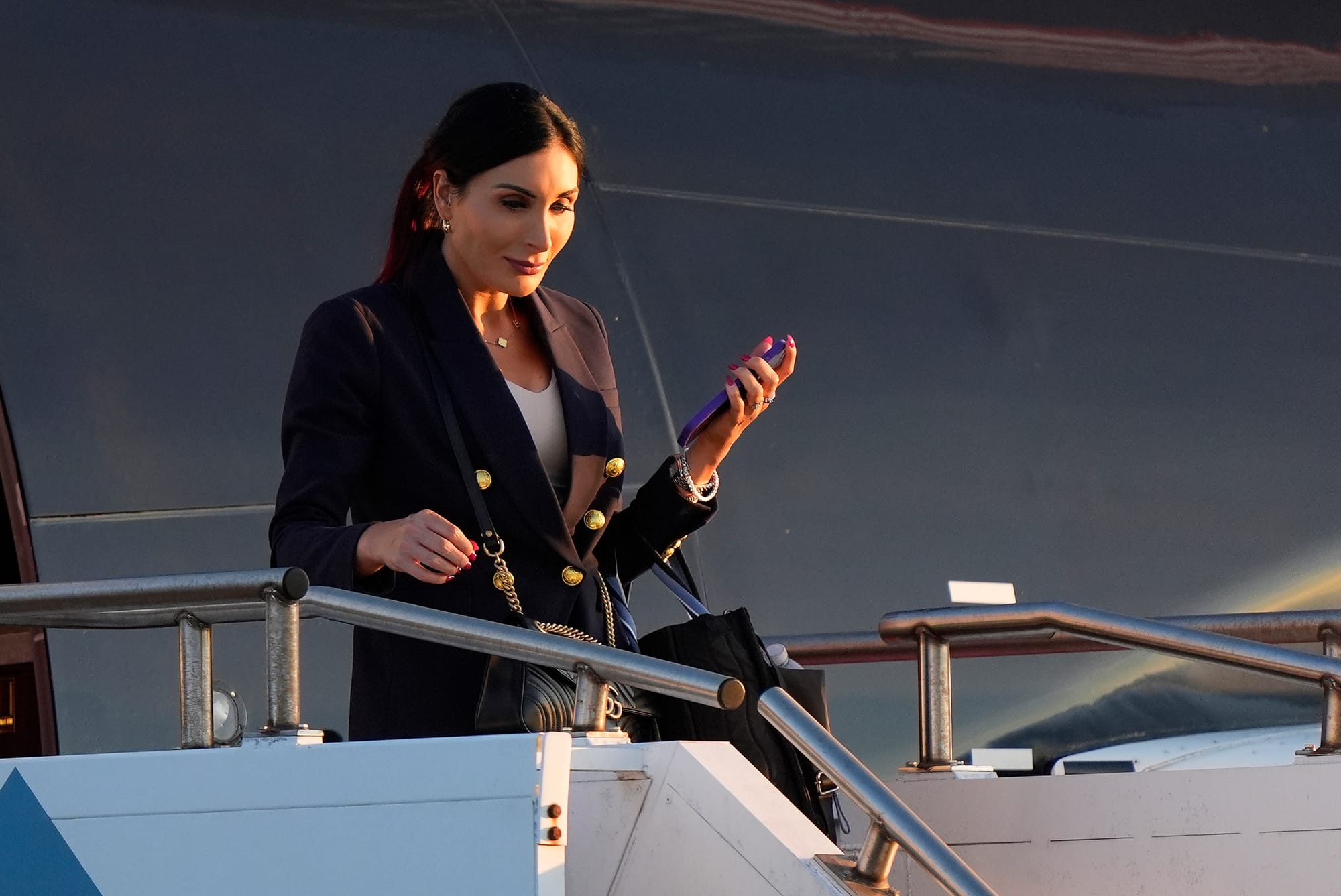 Laura Loomer steps off an airplane with a phone in her hand