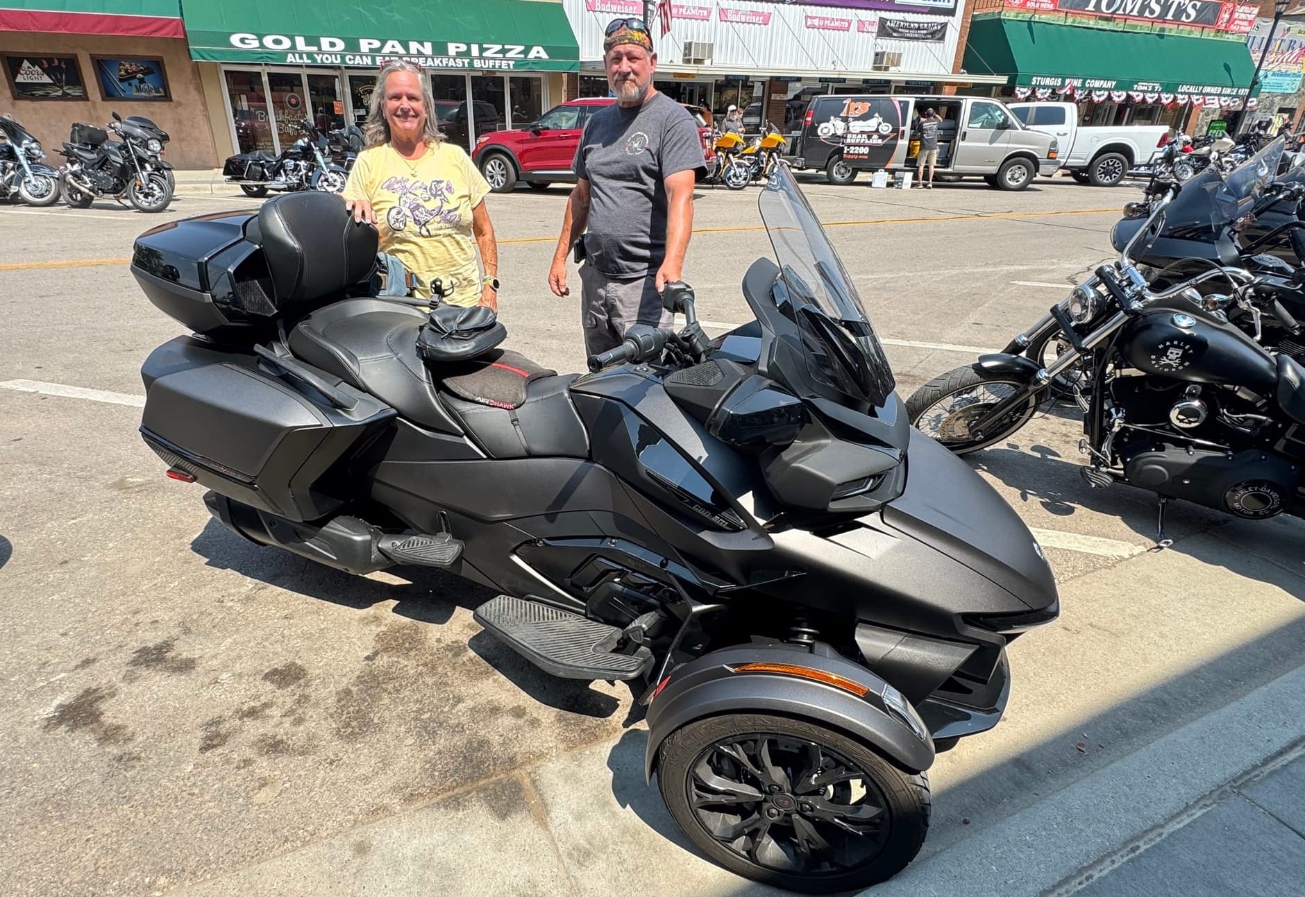 Sue and Craig Hillman stand by their Can-A Spyder three-wheeled motorcycle in downtown Sturgis, S.D., on Aug. 5, 2026.