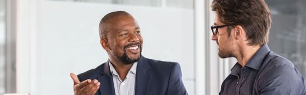 Black man in business suit speaking with a White man about retention in the company