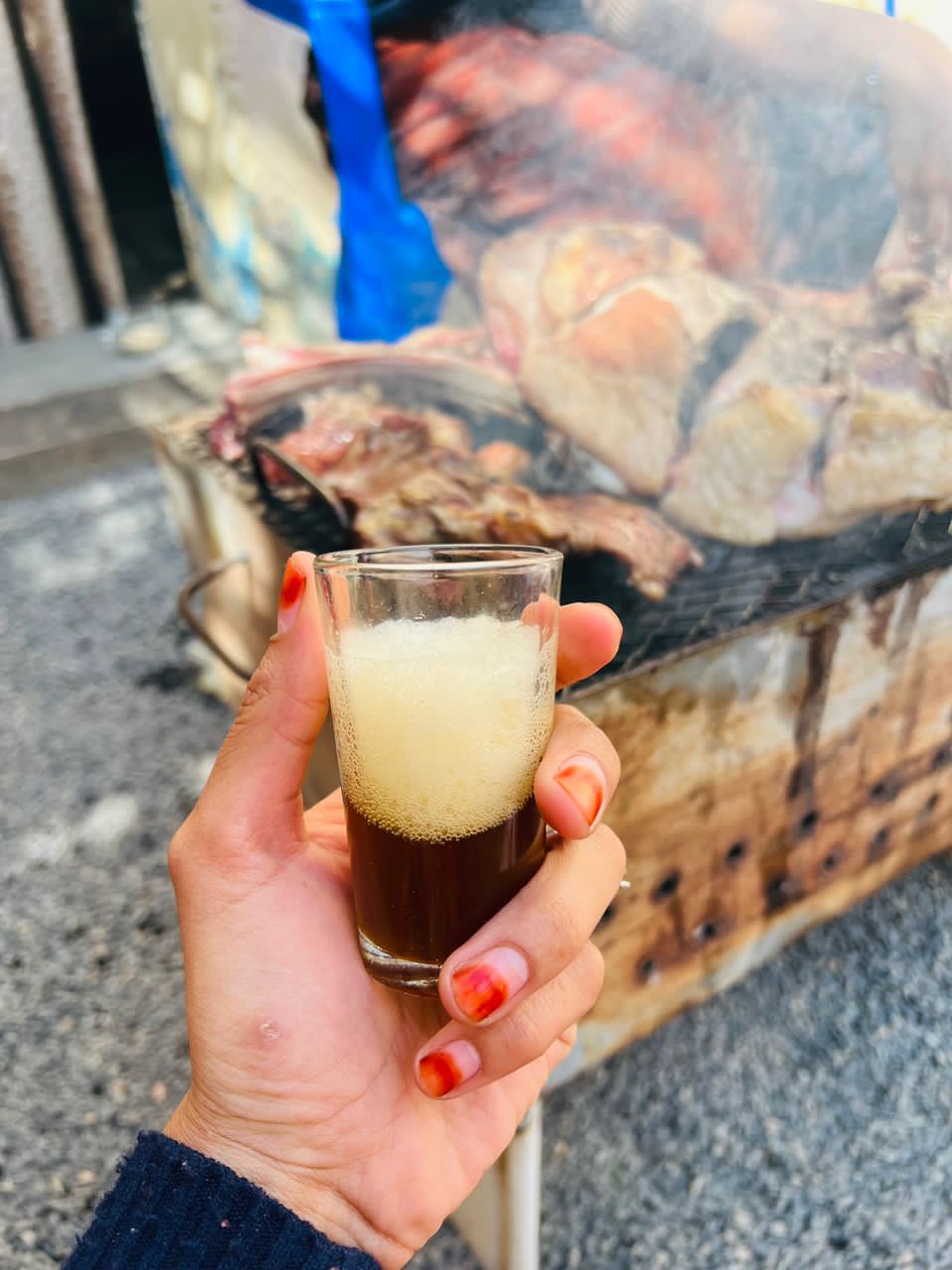 woman's hand holding glass of tea with foam