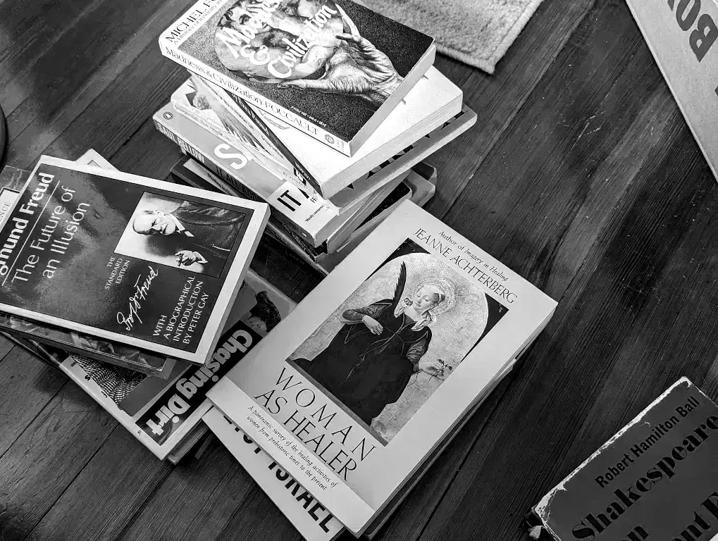 stacks of intellectually weighty books on floor alongside cardboard box