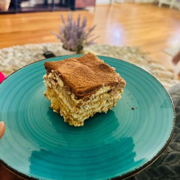 serving of layered tea biscuit and cream chocolate dessert on teal plate