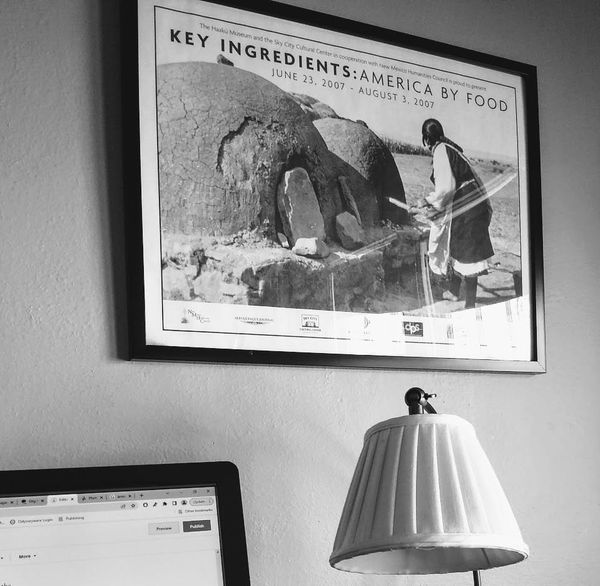 framed print from 2007 exhibit Key Ingredients: American by Food - photo of woman baking bread in earthen oven