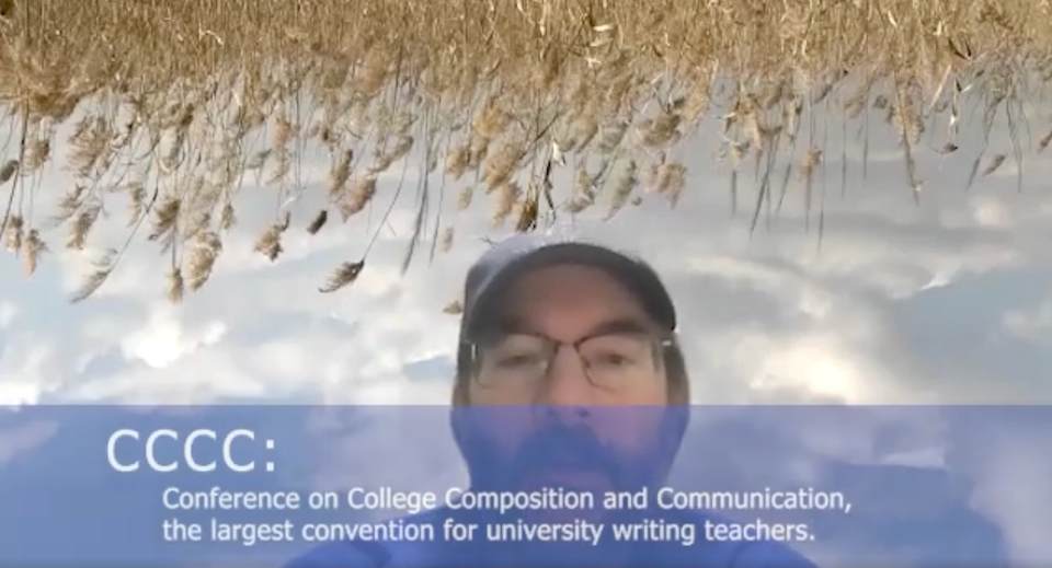 Doug peeking out from his upside-down field of wheat as his Zoom background. 