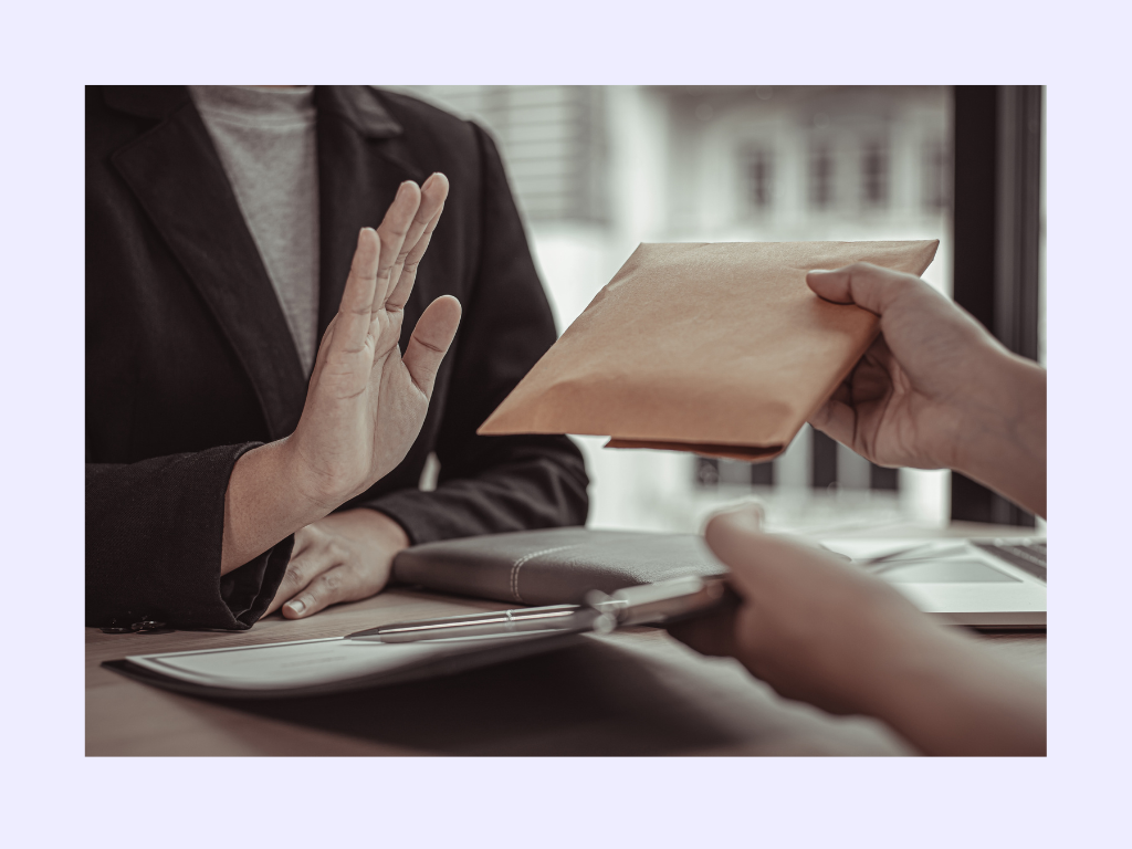 A person in a business setting politely refusing an envelope with a hand gesture, symbolizing the rejection of an offer