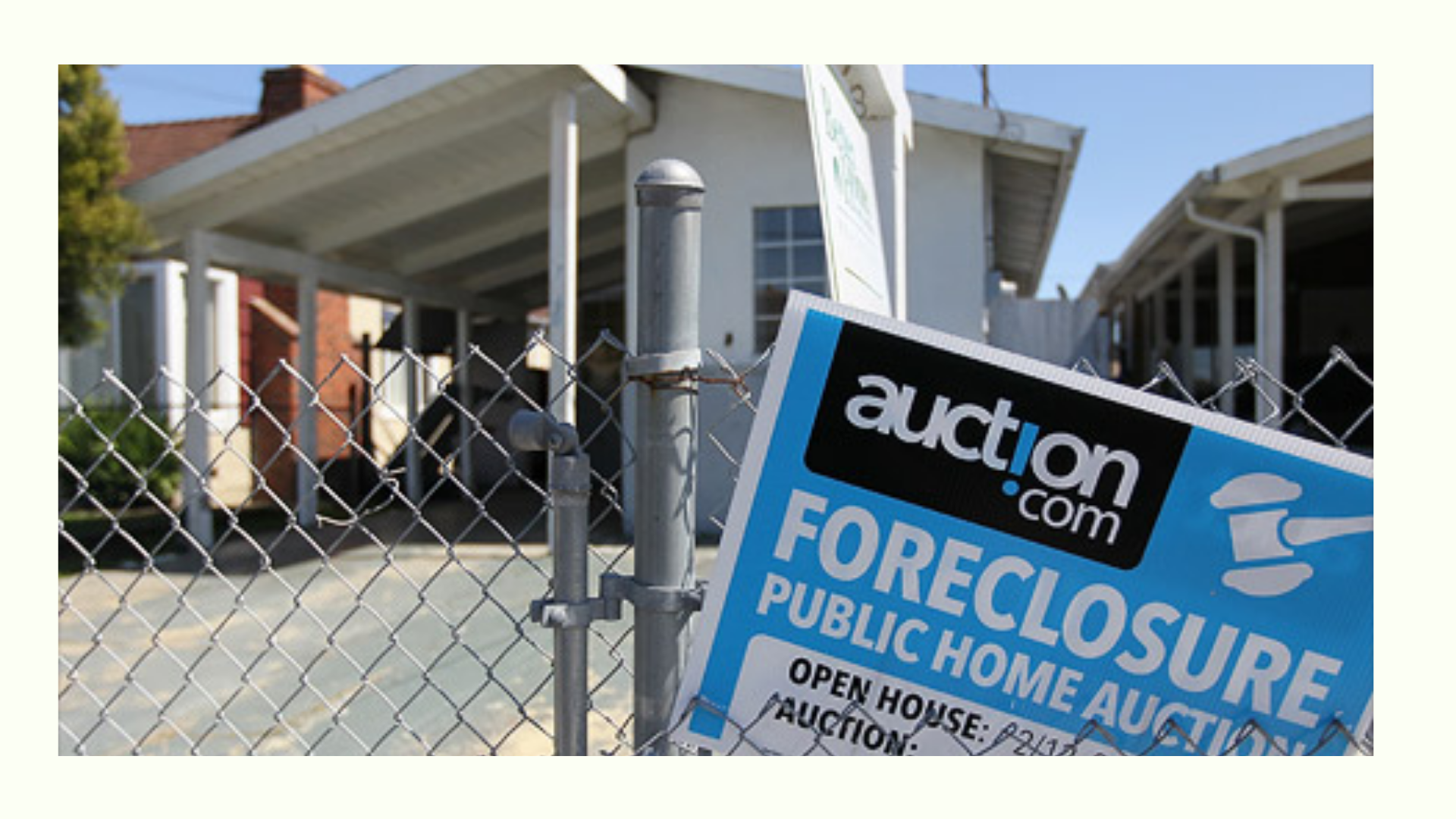 Foreclosed home with an auction.com sign on a chain-link fence, indicating a public home auction for the property.